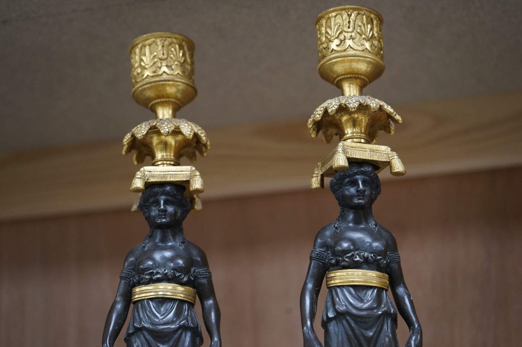 A pair of Regency bronze and gilt candlesticks in the form of standing classical figures mounted on marble bases, 31.5cm high.